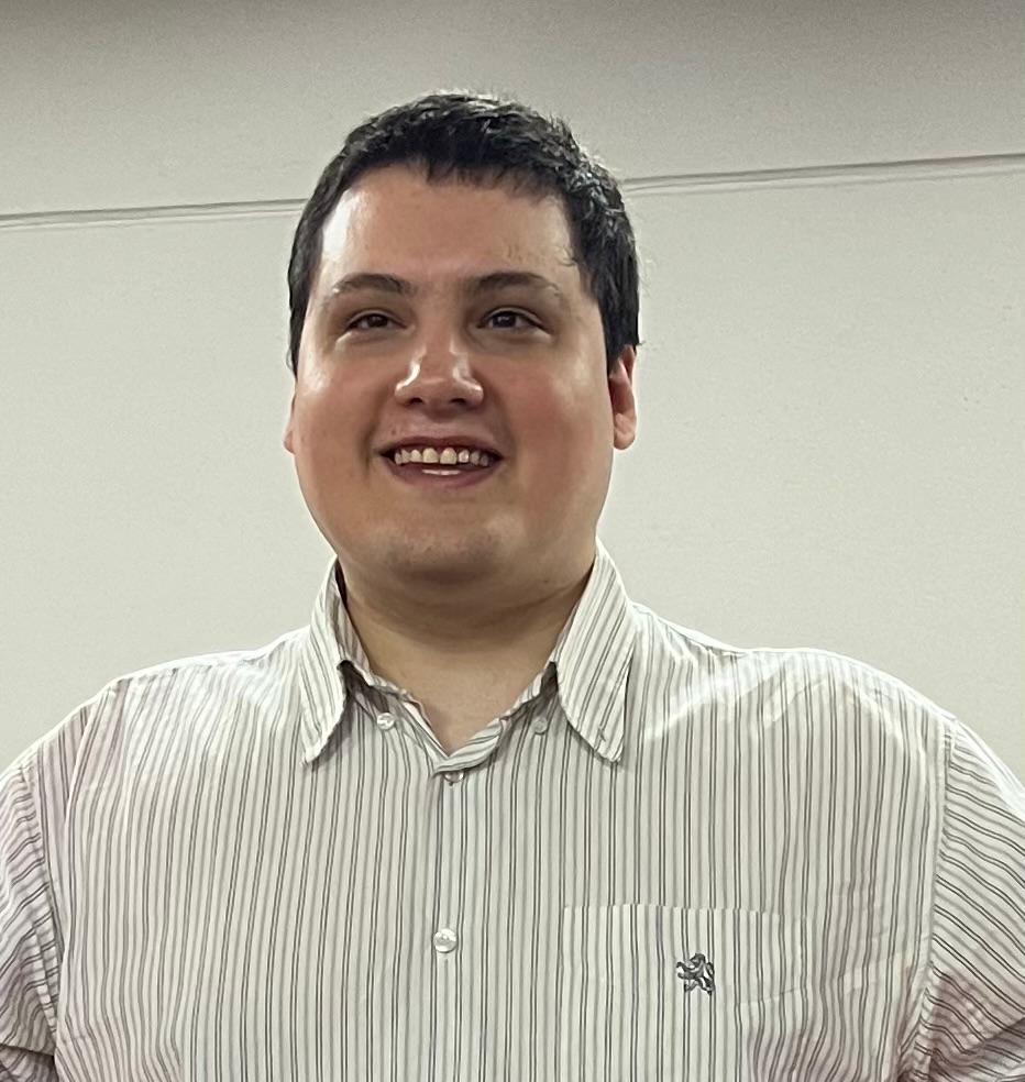 Foto mía sonriendo. Tengo el pelo oscuro y llevo una camisa a rayas.